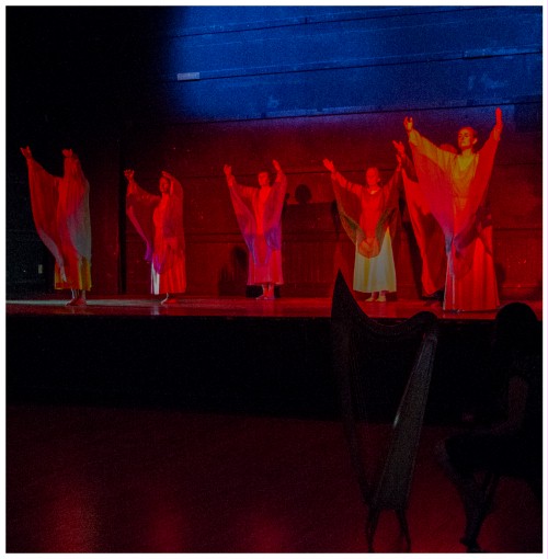 (Image: Dancers in Deep Red Raise their Arms)