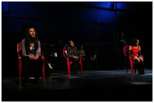 (Image: Three Seated Actors Sing, each from a Chair)