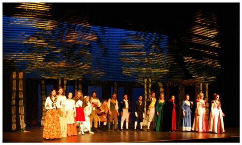 (Image: The Cast seen against a Blue Scrim and
  Yellow-Dappled Trees)