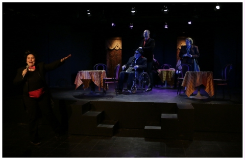 (Image: Harry Enters Pushing Tony in the
  Wheelchair followed by Annabel, while an MC croons to
  the Audience from the Main Floor)